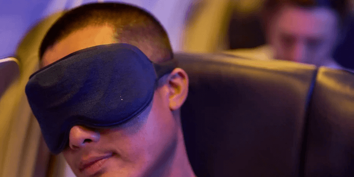 Person schläft mit einer Schlafmaske im Flugzeug Maske zum schlafen