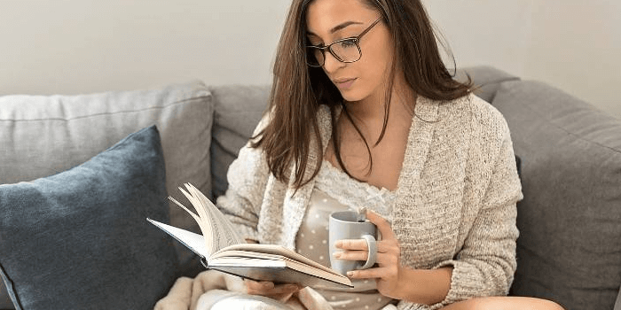 Frau liest ein Buch mit eine Tasse in der Hand Mehr Beweglichkeit & Energie im Alltag